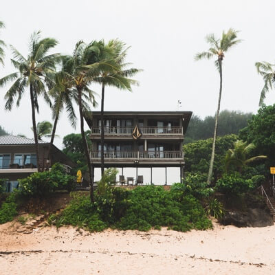 Photo of a beach house that has a large volcom logo displayed. Lots of foliage around the home