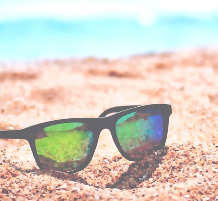 photo of sunglasses sitting in sand