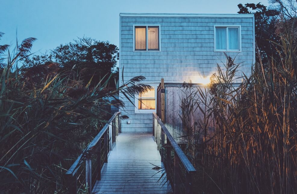 photo of a grey house in the dusk surrounded by foliage